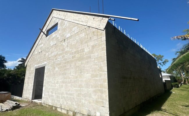 New concrete block building under construction with tie beam and rebar on a poured foundation in Southwest Florida